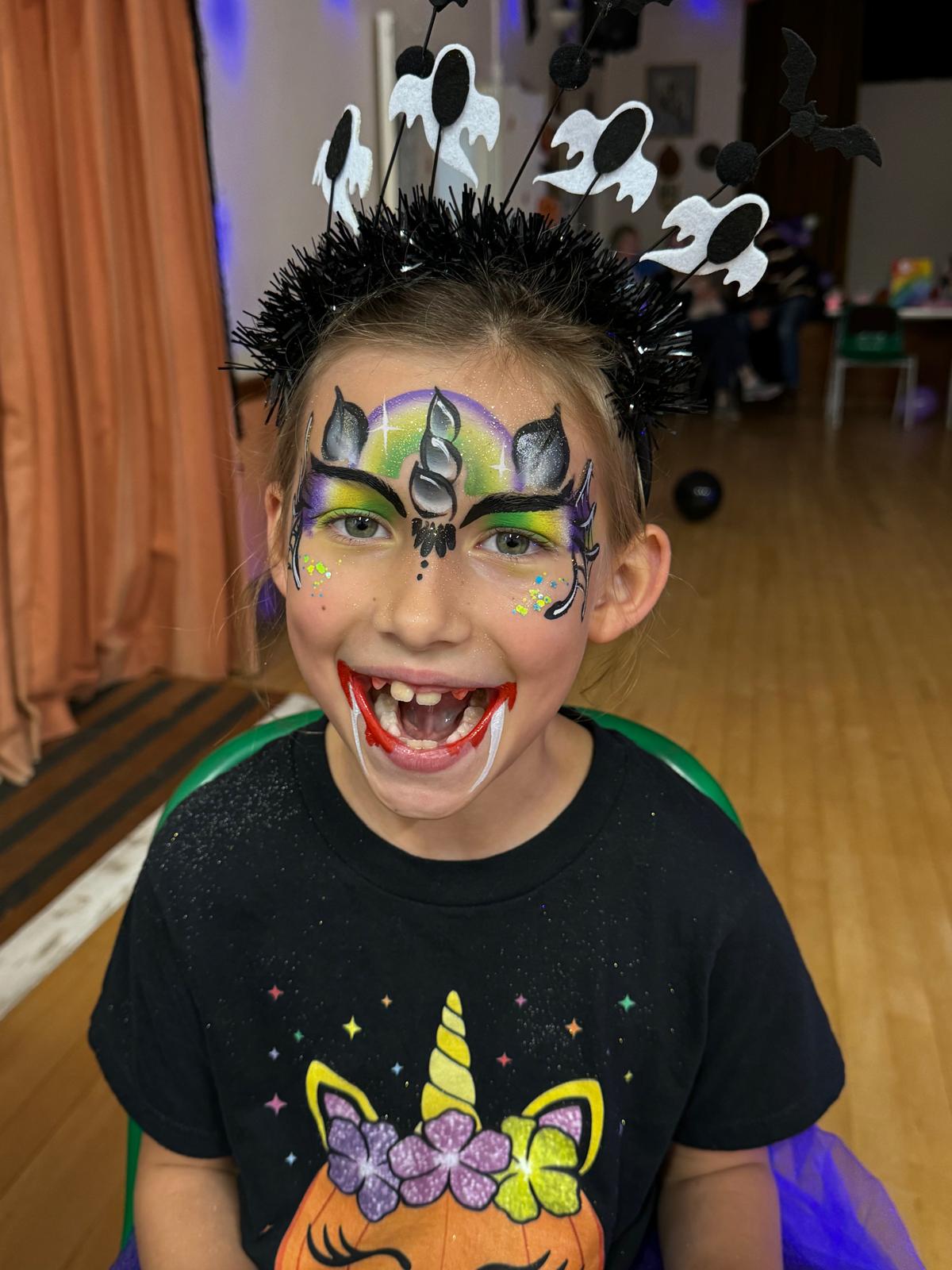 Halloween face painting — child with ghost headband and vampire fangs design